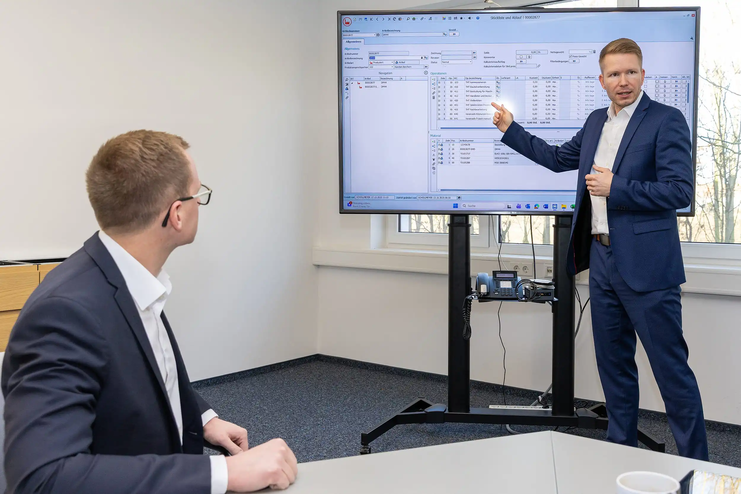 Ein Mitarbeiter von SE-TEC zeigt auf eine Tabelle auf einem Monitor im Besprechungsraum